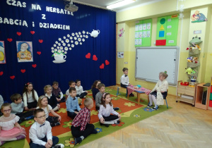 dzieci siedzą na dywanie