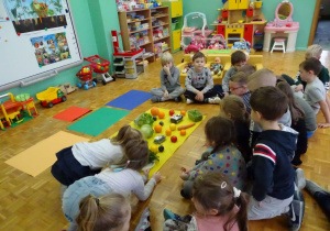 dzieci siedzą wokół warzyw i owoców