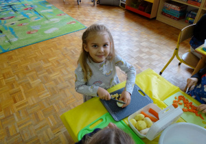 dziewczynka kroji warzywa na sałatkę