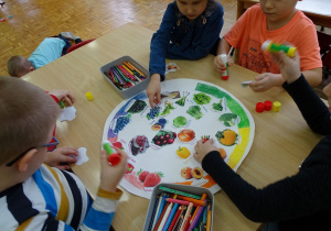 dzieci przyklejają zdjęcia warzyw i owoców