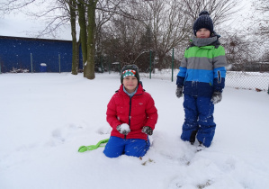 chłopiec trzyma śnieżkę, obok niego drugi stoi