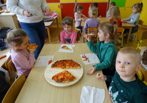 dzieci przy stoliczku jedzą pizze