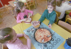 dzieci nakładają wybrane składniki na pizze