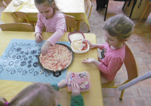 dziewczynki nakładaja składniki na pizze