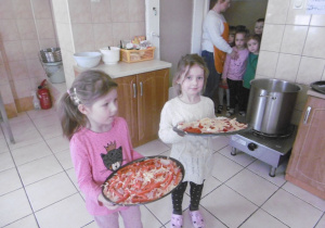 dziewczynki trzymaja gotową pizze