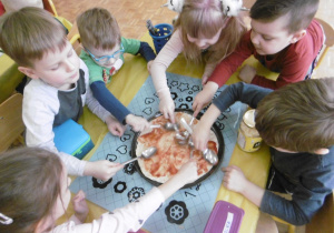 dzieci smarują pizze sosem pomidorowym