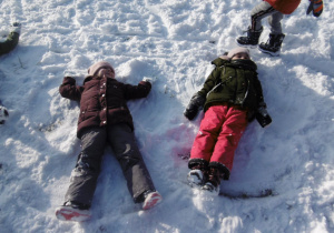 dzieci robią ,,aniołki,, na śniegu