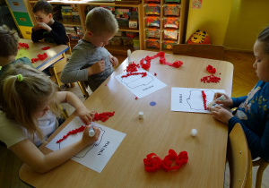 dzieci wyklejają kulkami szablon Polski