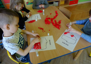 dzieci wyklejają kulkami szablon Polski