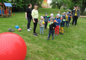 Rzucanie balonów wypełnionych przez dzieci do dużej piłki.