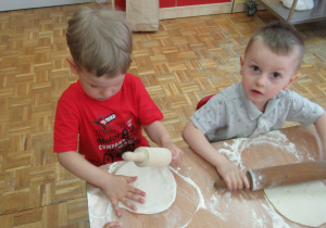 Dzieci wałkują ciasto na pizze.