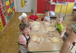 Dzieci oczekują na włożenie pizzy do piekarnika.